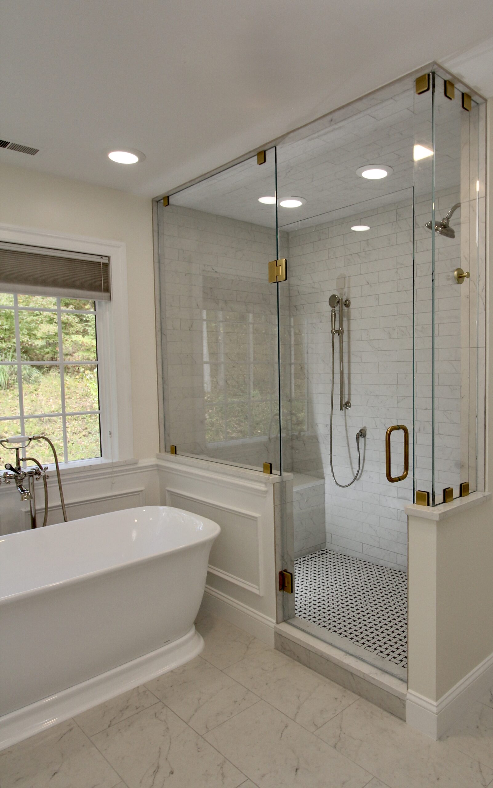 Modern bathroom featuring a glass shower, freestanding tub, and elegant tile work.